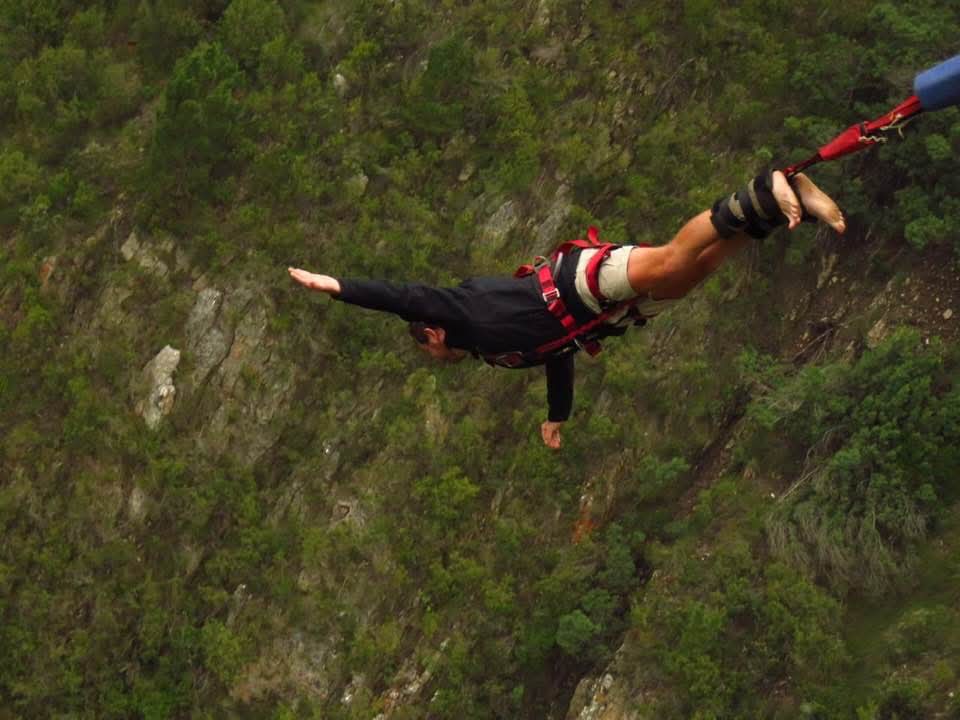 Angelo falling head-first over the tree-covered slopes during the bungy jump
